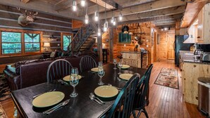 A rustic cabin interior with a dining area, wooden walls, a staircase, and a kitchen. - Water's Edge-Pet Friendly 3 Bedroom, Luxury Log Cabin Rental, Perfect for Families, Outdoor Entertaining, Hot Tub, Fireplace, 30 Minutes to Great Smoky Mountains-Nantahala NC (Topton)
