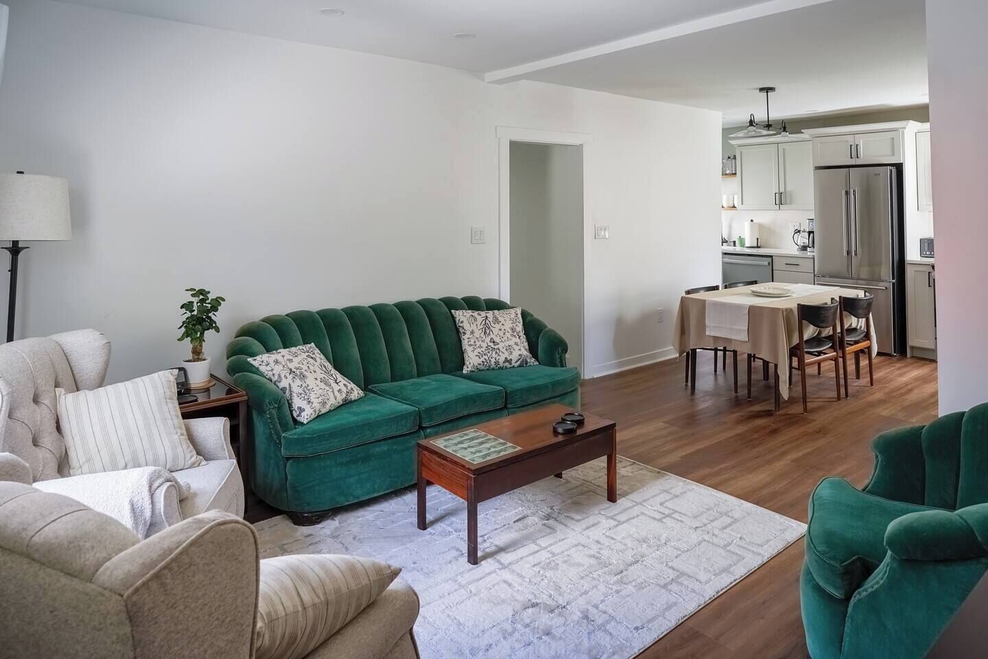 A living room with a green sofa, a coffee table, and a dining area with a table and chairs.