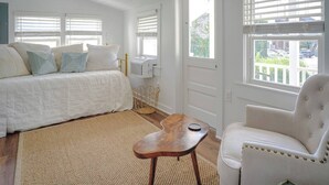 A bedroom with a bed, a chair, a small table, and a window with blinds. - Stylish Apt Walk to Shops, Dining and Bucknell (Lewisburg)