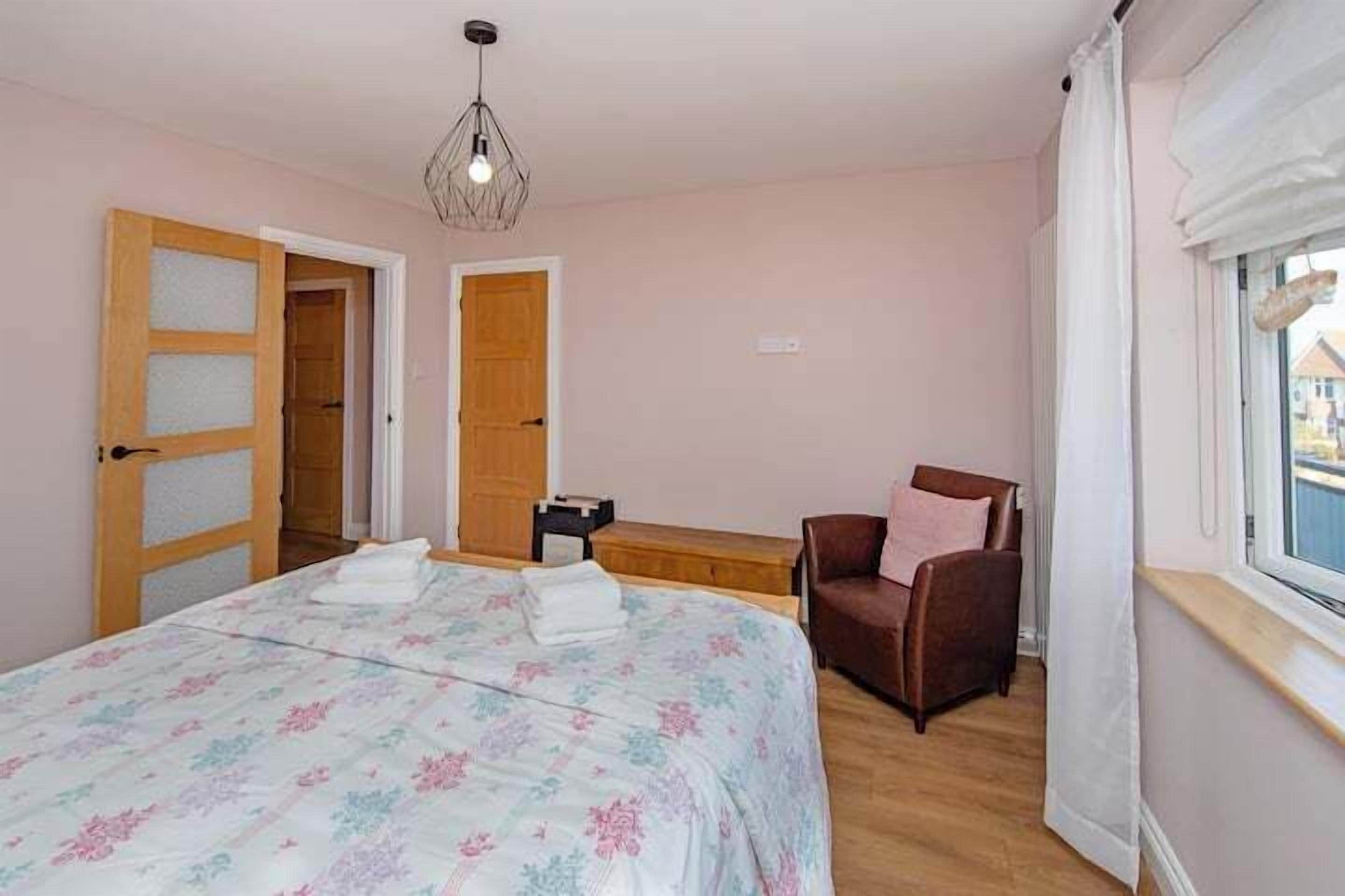 A bedroom with a bed, a chair, a window, and a door.
