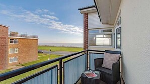 A balcony with a view of a brick building and a grassy area. - Coastal Charm In Clacton On Sea / With Balcony & Sea View / Sleeps 4 (Essex)