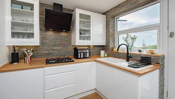 A modern kitchen with white cabinetry, a stone backsplash, a built-in stove, and a window with a view. - Coastal Charm In Clacton On Sea / With Balcony & Sea View / Sleeps 4 (Essex)