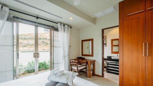 A hotel room with a bed, a desk, a mirror, and a wardrobe. - Ivory Pool Villa in Nai Harn (Phuket)