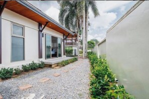 A modern house with a covered porch, a gravel pathway, and a well-maintained garden. - Ivory Pool Villa in Nai Harn (Phuket)