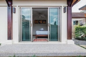 A room with a bed, a ceiling fan, and a view of the outdoors. - Ivory Pool Villa in Nai Harn (Phuket)