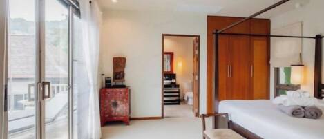 Habitación de hotel con cama, un banco, cómoda y vistas a través de un ventanal grande.