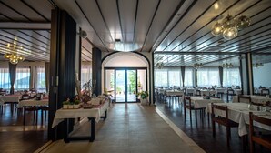 Un restaurant spacieux doté d’une arche centrale qui mène à un espace extérieur, de nombreuses tables et d’un éclairage moderne.