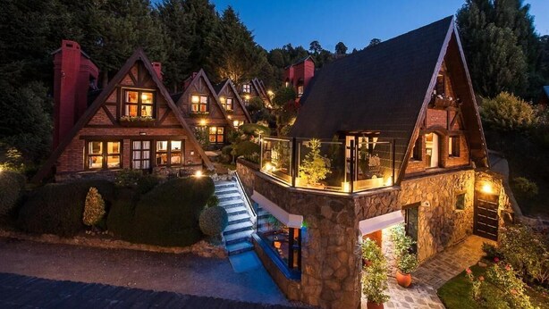 Una hilera de cabañas de madera con cimientos de piedra, cada una con un balcón y una escalera que lleva a la entrada.