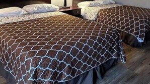 Une chambre d’hôtel avec deux lits, une table de chevet avec une lampe et des œuvres d’art encadrées accrochées aux murs.