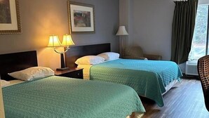 Une chambre d’hôtel avec deux lits, une table de chevet avec des lampes, une chaise et une fenêtre avec des rideaux.