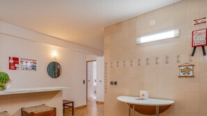 A kitchen with a white countertop, a bowl of fruit, a mirror, and a small table.