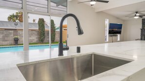 Una cucina moderna con un lavello grande, una ventola a soffitto e una TV montata a parete.