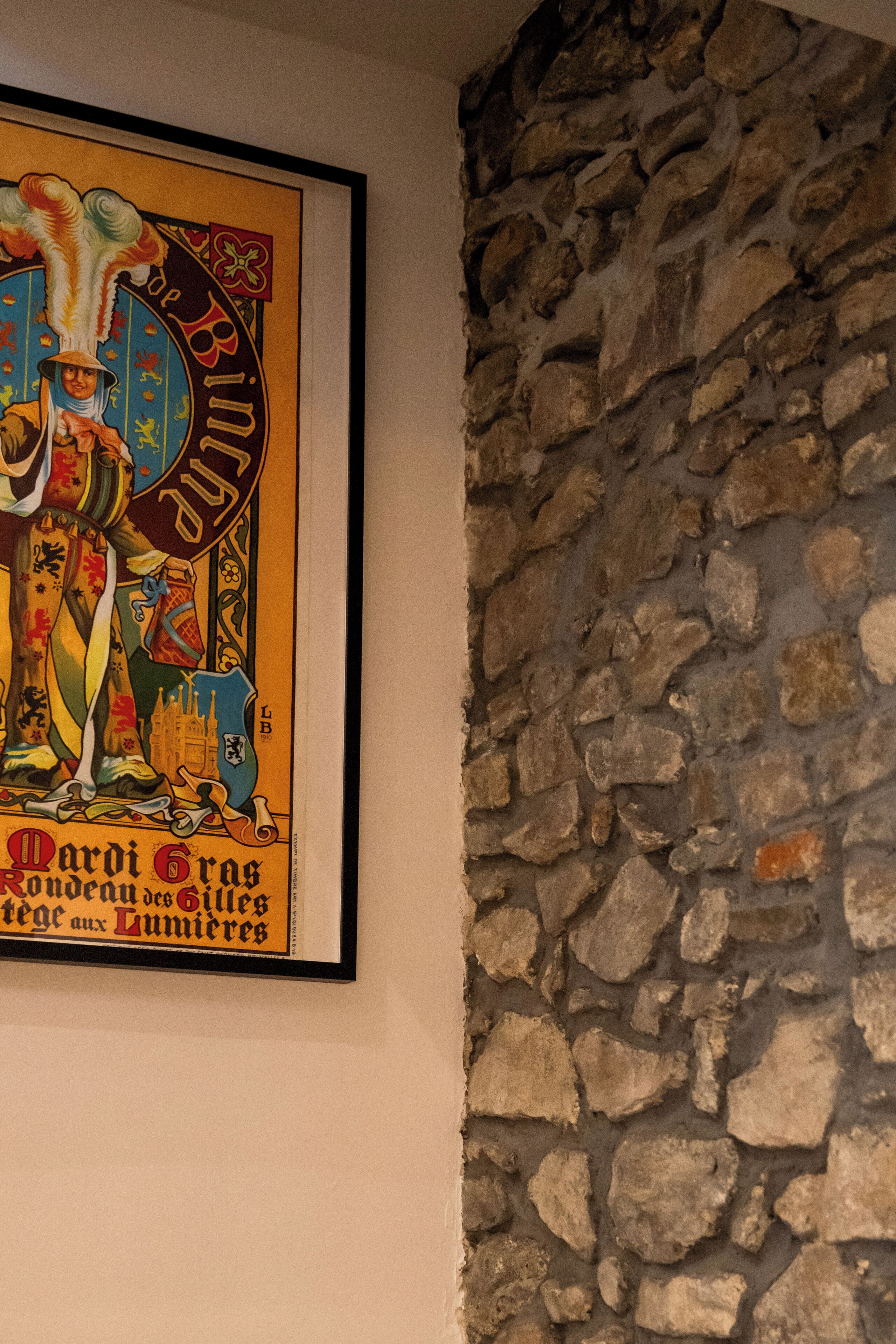 A framed poster with a colorful elephant and text, mounted on a wall with a stone wall backdrop.