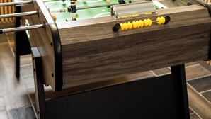 Ein Kicker-Tisch in einem Raum mit Holzvertäfelung und einem Fenster.