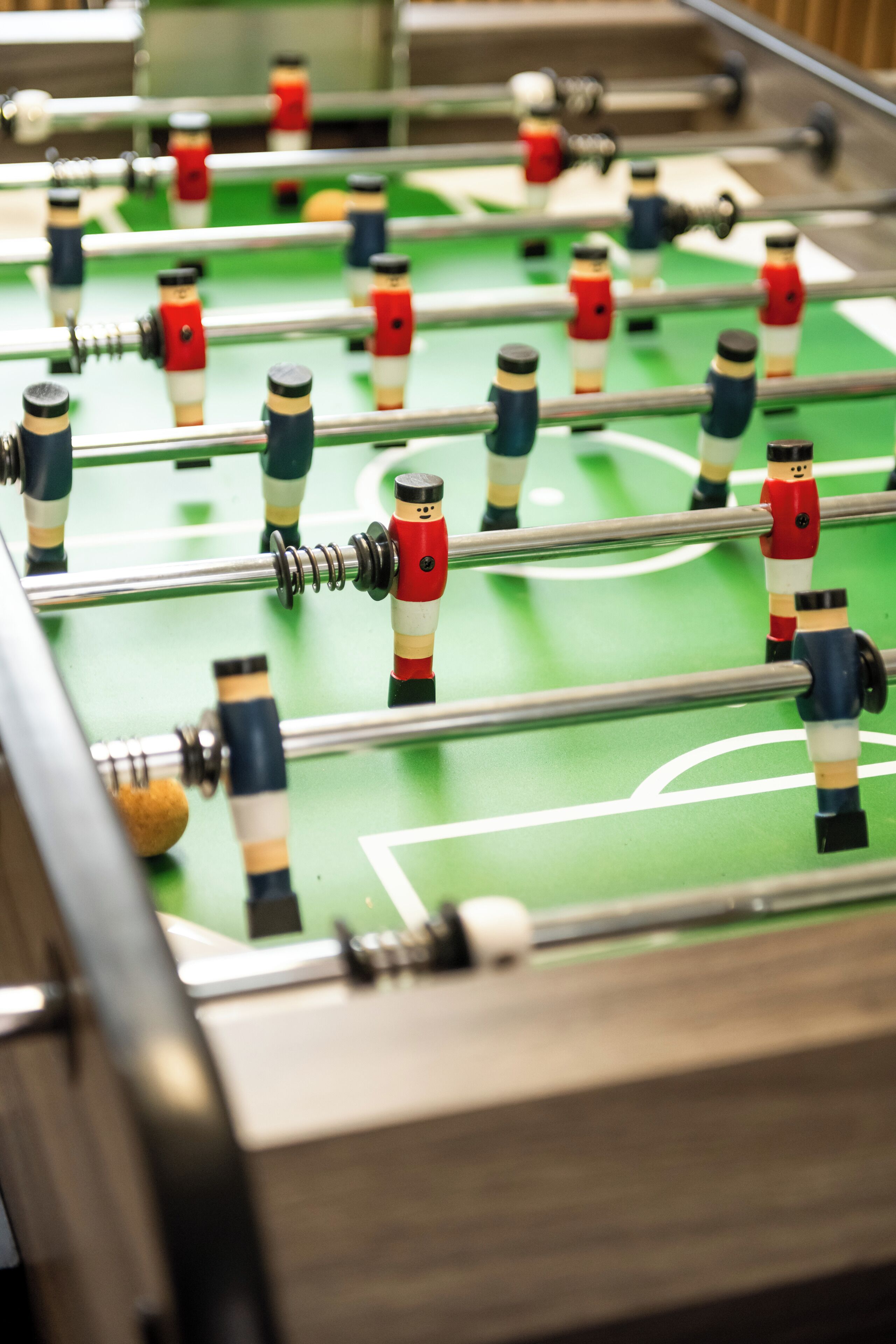 A close-up of a foosball table with a green playing surface and metal rods.