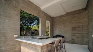 A modern kitchen with a large island, bar stools, and a view of the outdoors.