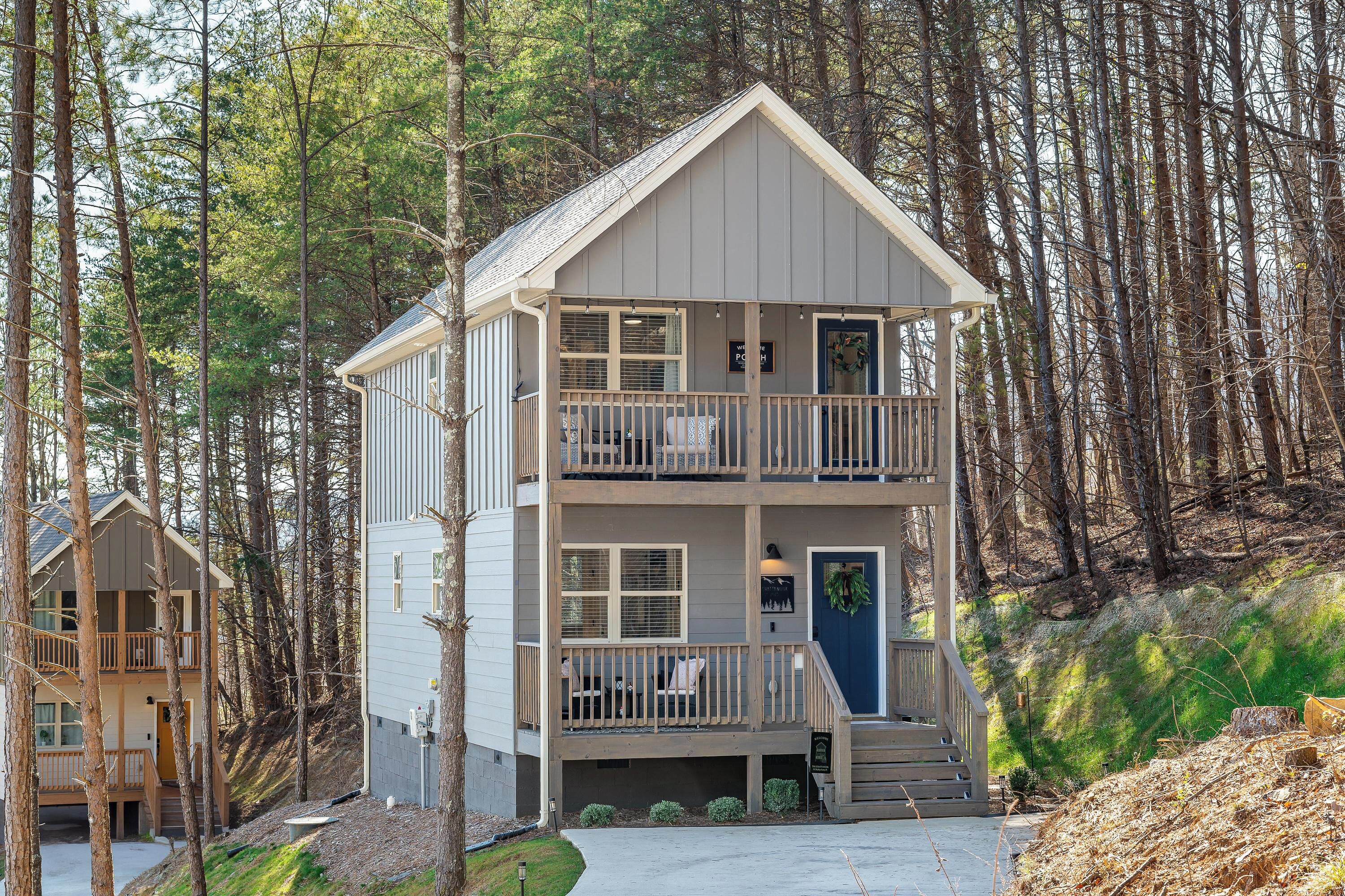 A two-story cabin with a balcony, surrounded by trees.