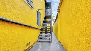 A narrow alleyway with a metal staircase leading upwards, flanked by yellow walls. - 8 Mi to Dtwn LA: Apt w/ Shared Patio! (Los Angeles)