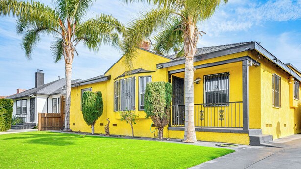 A yellow house with a well-maintained lawn and palm trees. - 8 Mi to Dtwn LA: Apt w/ Shared Patio! (Los Angeles)