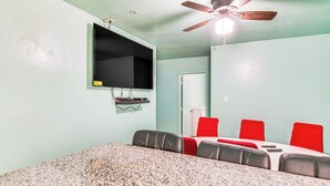 A room with a granite countertop, a ceiling fan, a mounted TV, and red chairs around a table. - 8 Mi to Dtwn LA: Apt w/ Shared Patio! (Los Angeles)