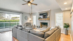 A spacious living room with a sectional sofa, a fireplace, and a ceiling fan. - 1 Mi to Broadway at the Beach: Home w/ Large Yard! (Myrtle Beach)