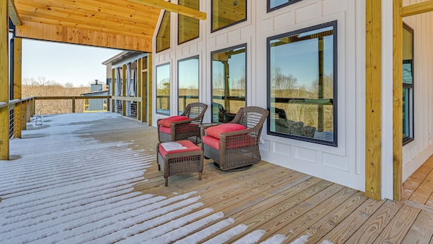 A covered deck with wicker chairs and a wooden railing. - Spacious Home in Paradise Grove Nolin Lake! (Clarkson)