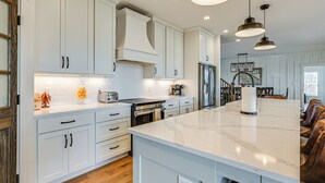 A modern kitchen with white cabinetry, a marble island, and pendant lighting. - Spacious Home in Paradise Grove Nolin Lake! (Clarkson)