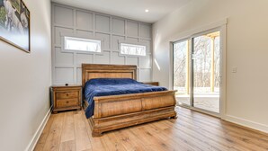 A bedroom with a wooden bed, a nightstand, a dresser, and a large window with a view of trees. - Spacious Home in Paradise Grove Nolin Lake! (Clarkson)