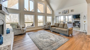 A spacious living room with a fireplace, large windows, and a high ceiling. - Spacious Home in Paradise Grove Nolin Lake! (Clarkson)