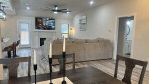 Een moderne woonkamer met een eethoek, een open haard en een plafondventilator.