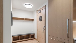 Un baño moderno con un mueble de tocador de madera, un banco y un estante en la pared.