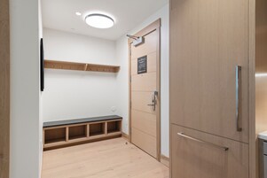 Un baño moderno con un mueble de tocador de madera, un banco y un estante en la pared.
