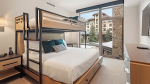 Una habitación de hotel moderna con una cama individual, un escritorio con computadora y un ventanal con vistas a la ciudad.