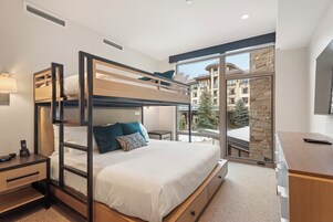 Una habitación de hotel moderna con una cama individual, un escritorio con computadora y un ventanal con vistas a la ciudad.