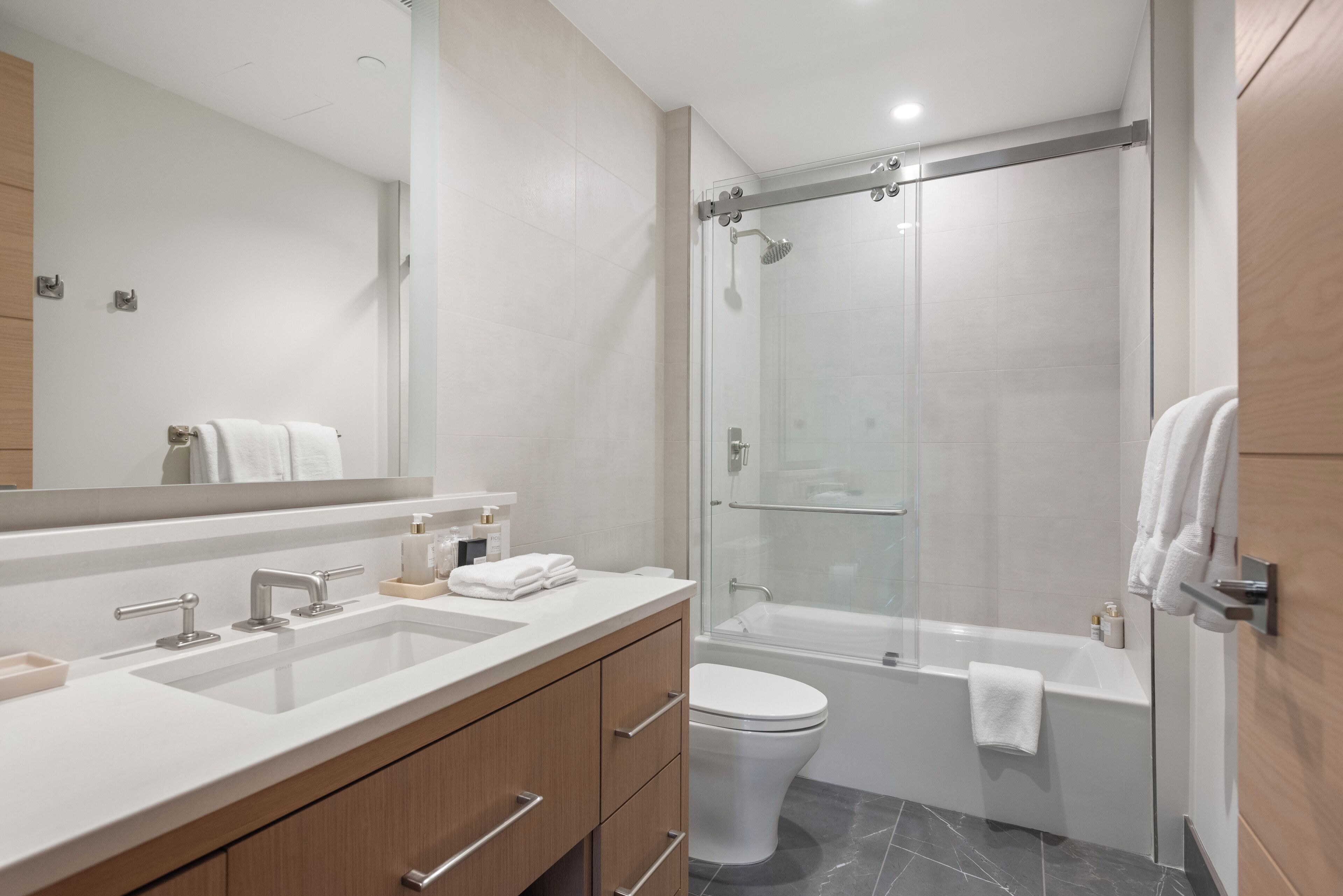 Une salle de bain moderne dotée d’une douche à parois de verre, d’une baignoire et d’un meuble-lavabo à deux vasques.