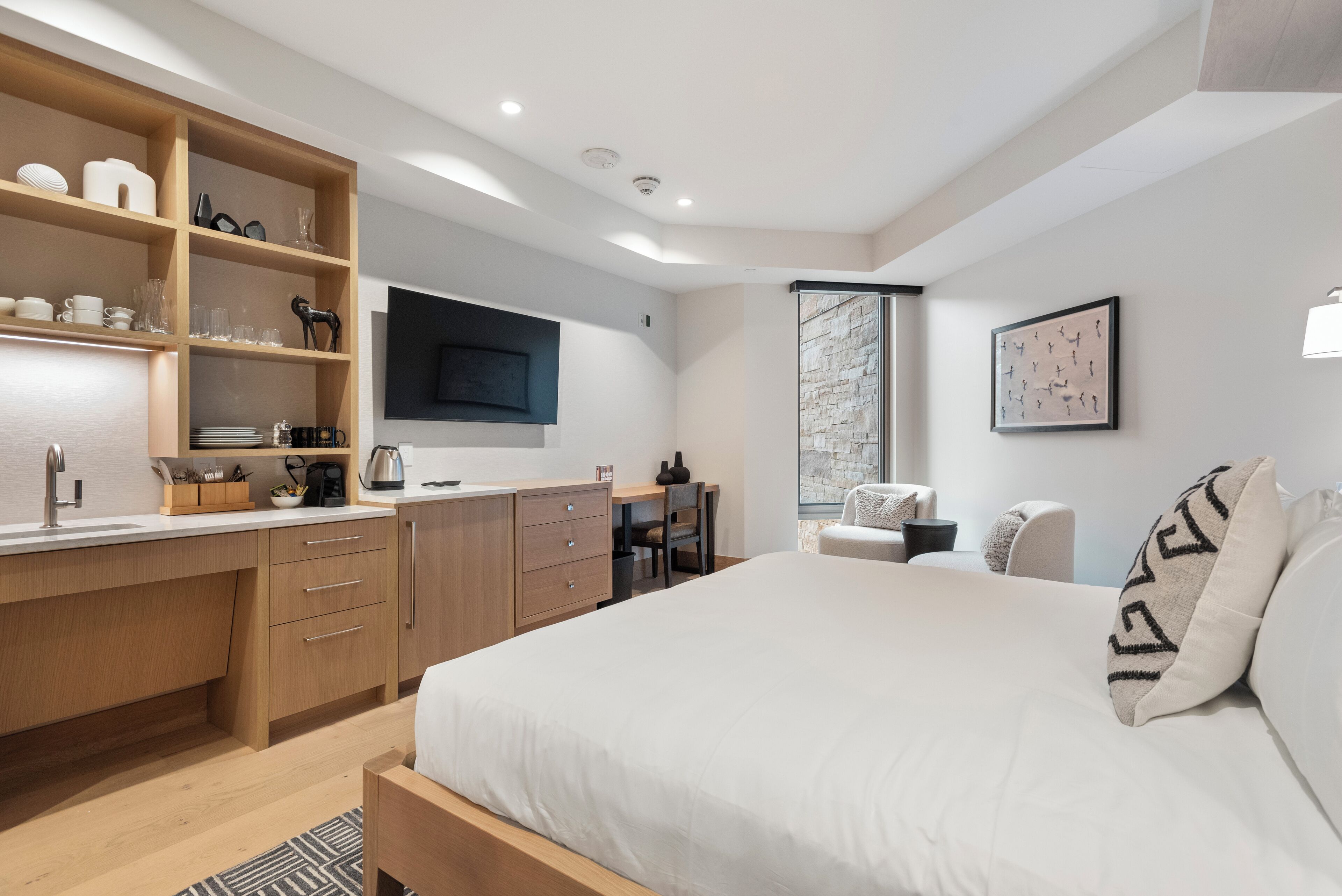 Un dormitorio moderno con una cama grande, un escritorio de madera y estanterías empotradas.
