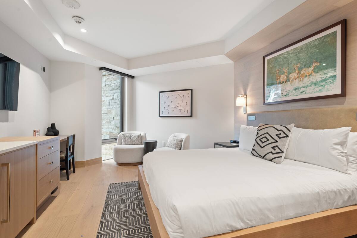 Een moderne slaapkamer met een groot bed, een bureau en een stoel.
