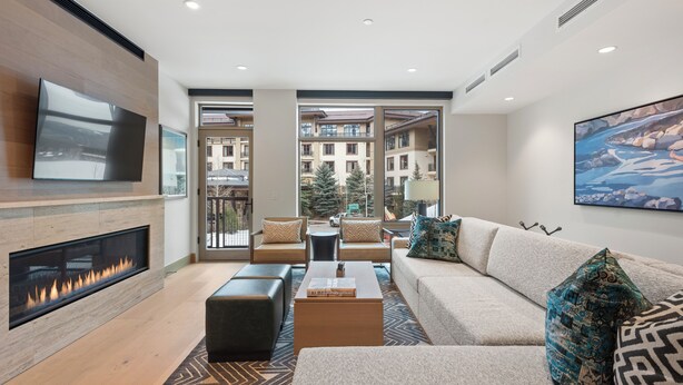 Una sala de estar moderna con chimenea, asientos cómodos y grandes ventanales que ofrecen vista a la ciudad.