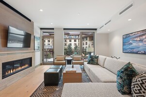 Una sala de estar moderna con chimenea, asientos cómodos y grandes ventanales que ofrecen vista a la ciudad.