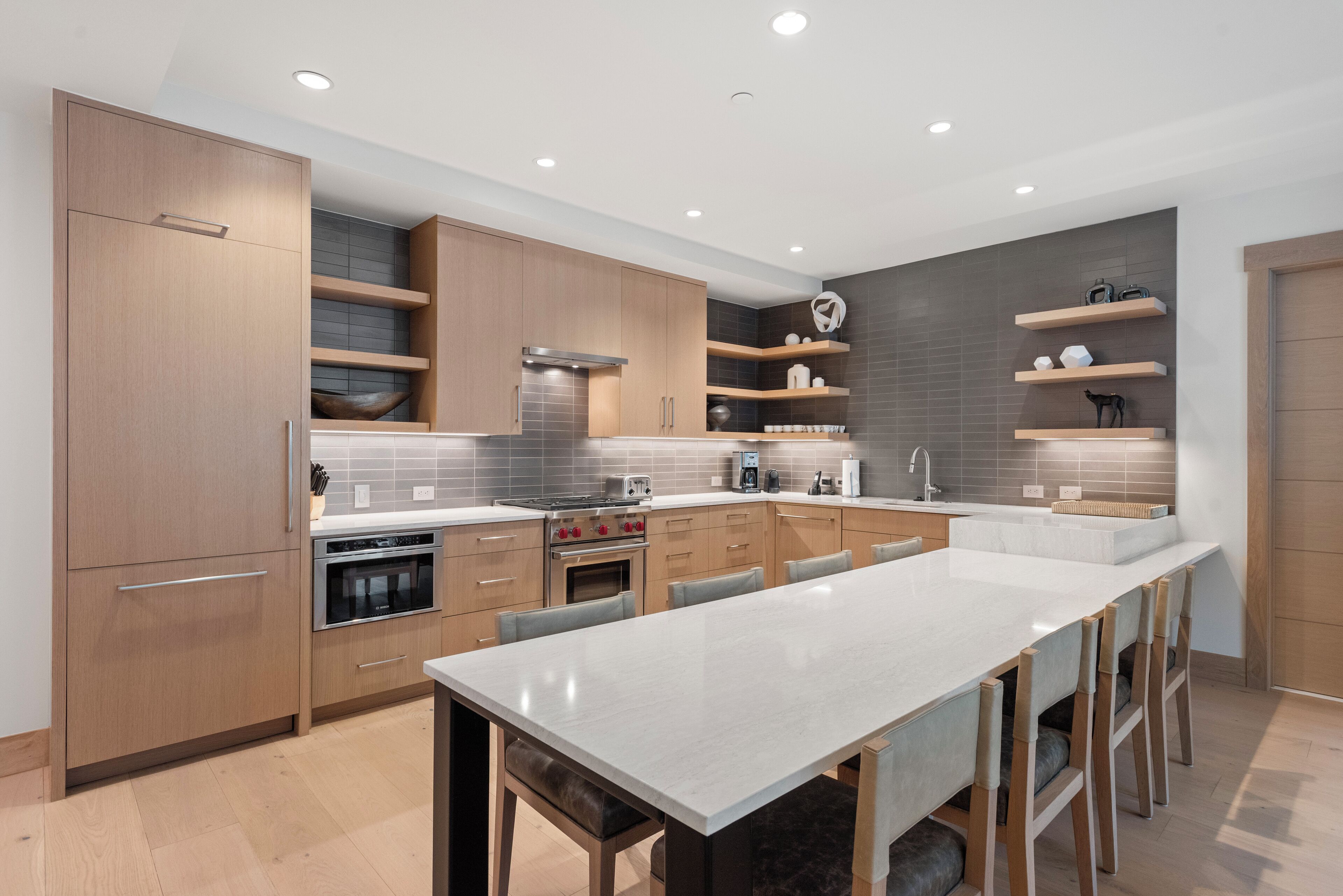 Une cuisine moderne avec des meubles en bois, un îlot central et des appareils électroménagers intégrés.