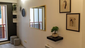 A hallway with a mirror, framed artwork, a potted plant, and a radiator. - Cozy Melbourne Studio Digital Detox Space (Melbourne)