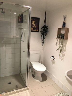 A bathroom with a glass-enclosed shower, a white toilet, a sink, and a framed picture on the wall. - Cozy Melbourne Studio Digital Detox Space (Melbourne)