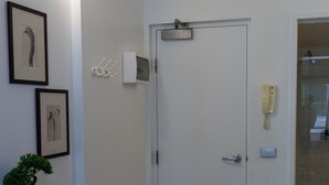 A hallway with a white door, a wall-mounted telephone, and framed artwork. - Cozy Melbourne Studio Digital Detox Space (Melbourne)