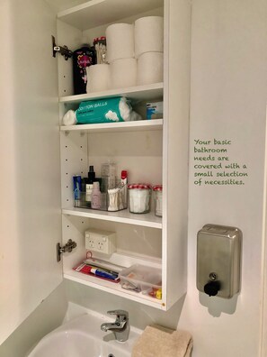 A bathroom with a shelf containing toiletries, a toilet paper roll, and a hand dryer. - Cozy Melbourne Studio Digital Detox Space (Melbourne)