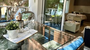 A glass-top dining table with a potted plant, wine glasses, and a bottle.