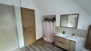 Une salle de bain moderne avec une douche, un lavabo et un miroir.
