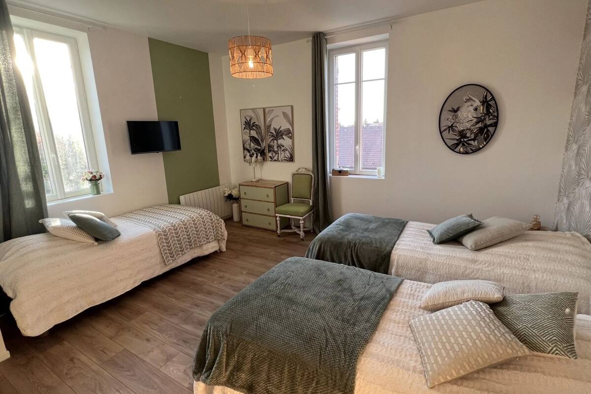 A bedroom with two beds, a dresser, a chair, a television, and artwork on the walls.