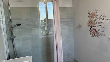 Une salle de bain moderne avec une douche à parois de verre, une baignoire blanche et un mur décoratif orné de motifs floraux.