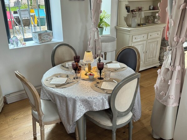 Mesa de jantar posta com pratos, talheres e copos, rodeada por cadeiras.