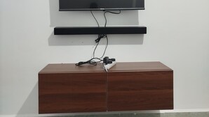 A flat-screen TV mounted on a wall above a wooden cabinet.
